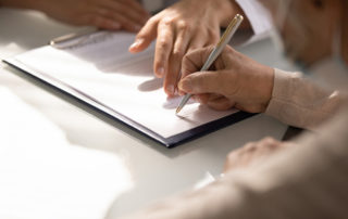 Person signing documents on a clipboard