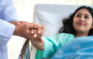 female patient holding physicians hands